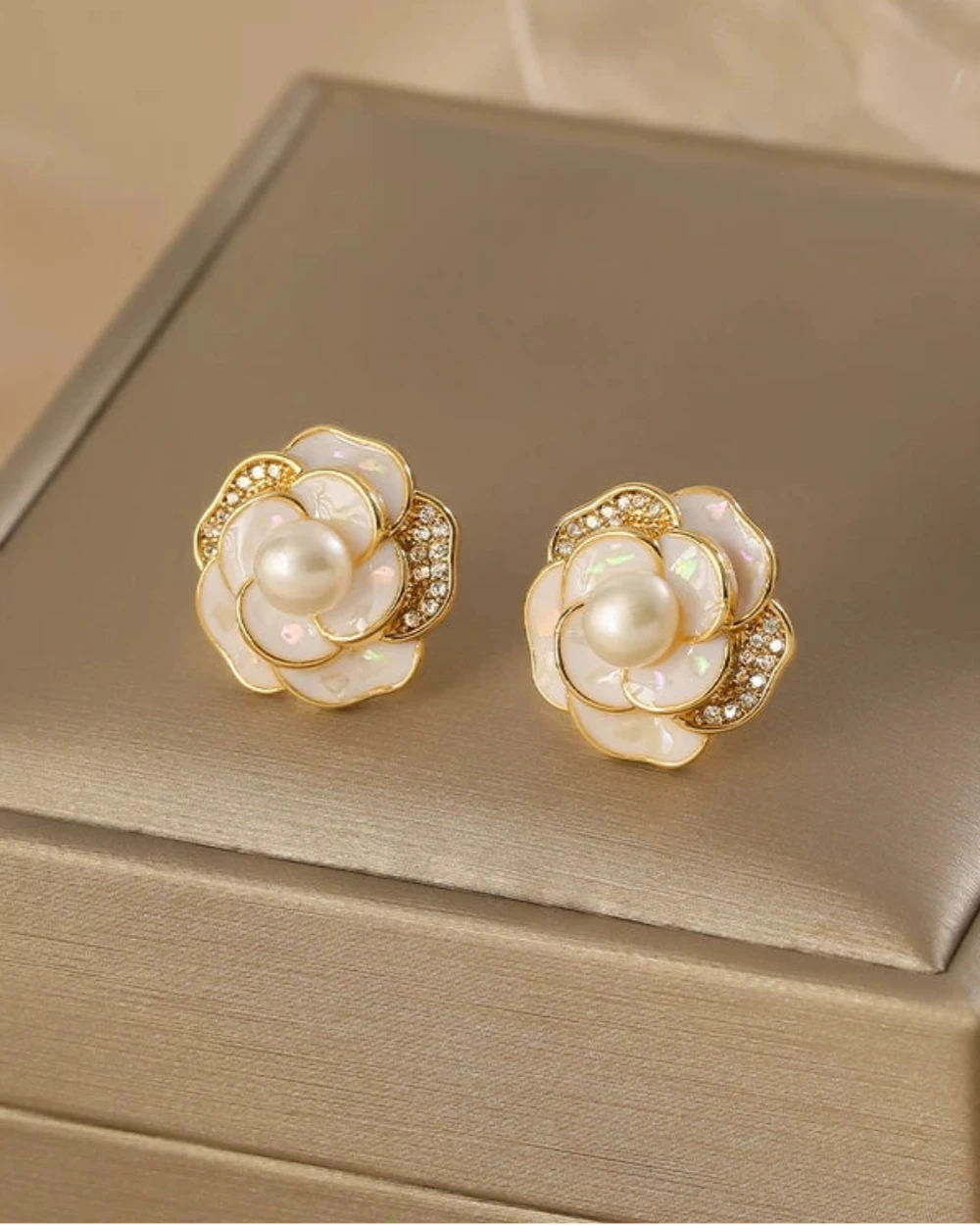 Pair of floral earrings with pearls on a beige jewelry box