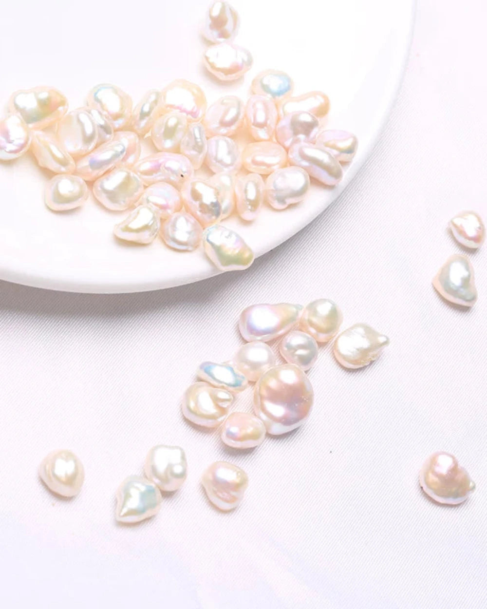 Pearls on a white plate and scattered on a light gray surface