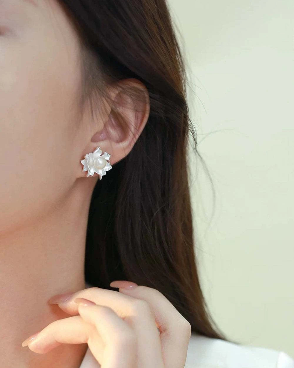 Close-up of a person wearing a silver floral earring with a blurred background