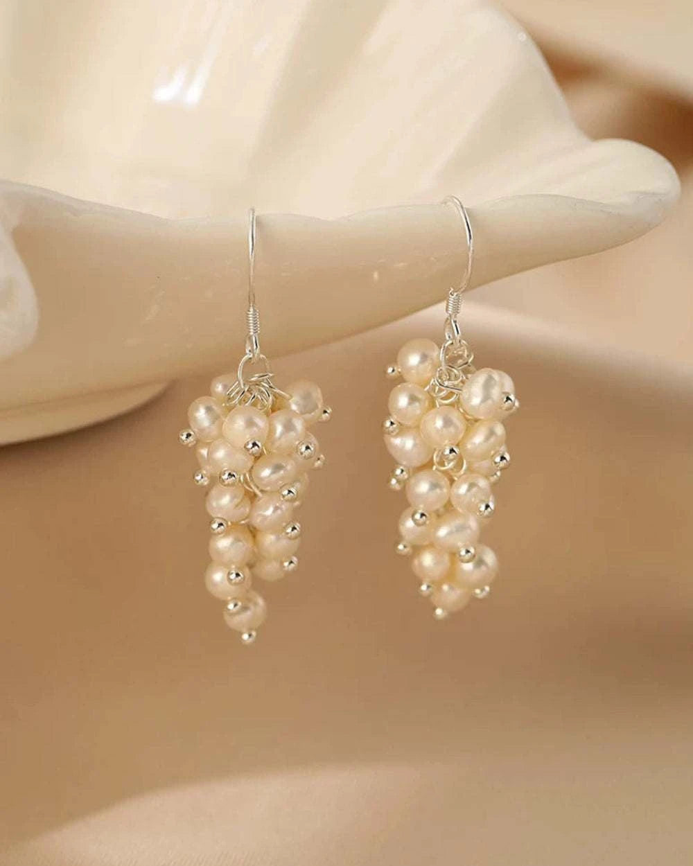 Pearl grape-shaped earrings on a beige background