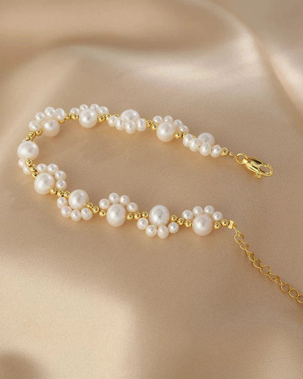 Pearl bracelet with gold chain on a beige fabric background