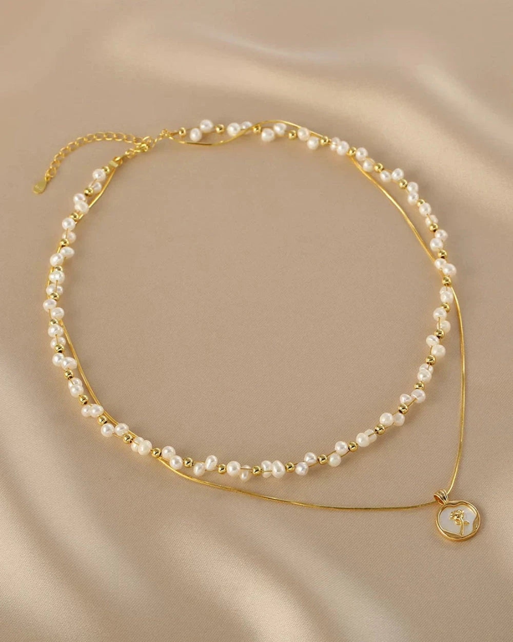 Gold and pearl necklace on a beige background