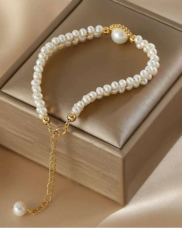 Pearl bracelet with gold chain on a beige box