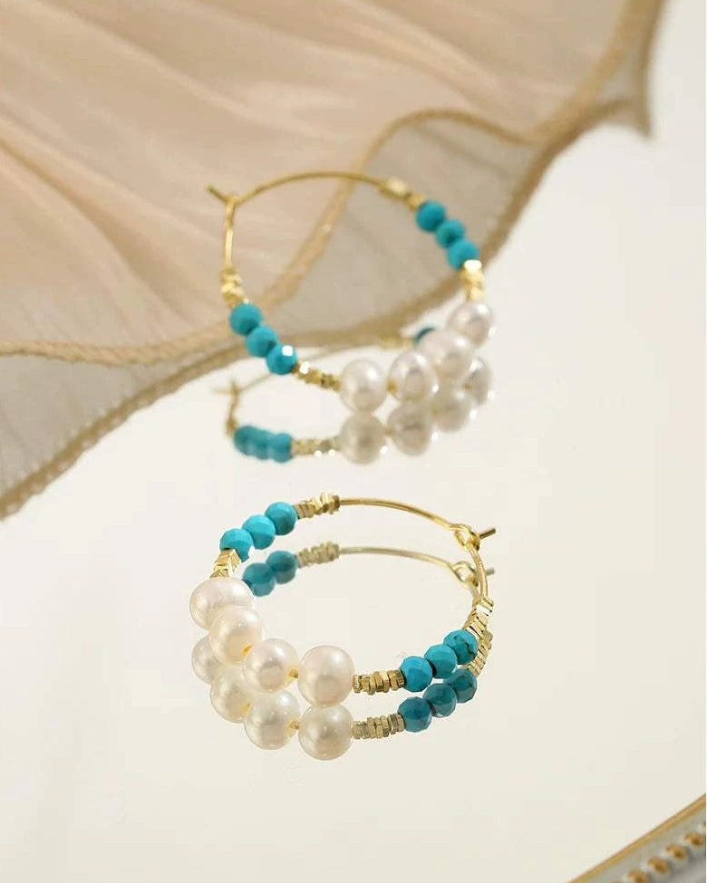 Pair of hoop earrings with pearls and turquoise beads on a neutral background
