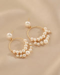 Gold hoop earrings with pearls on a beige background