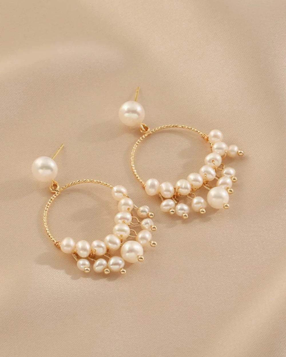 Gold hoop earrings with pearls on a beige background