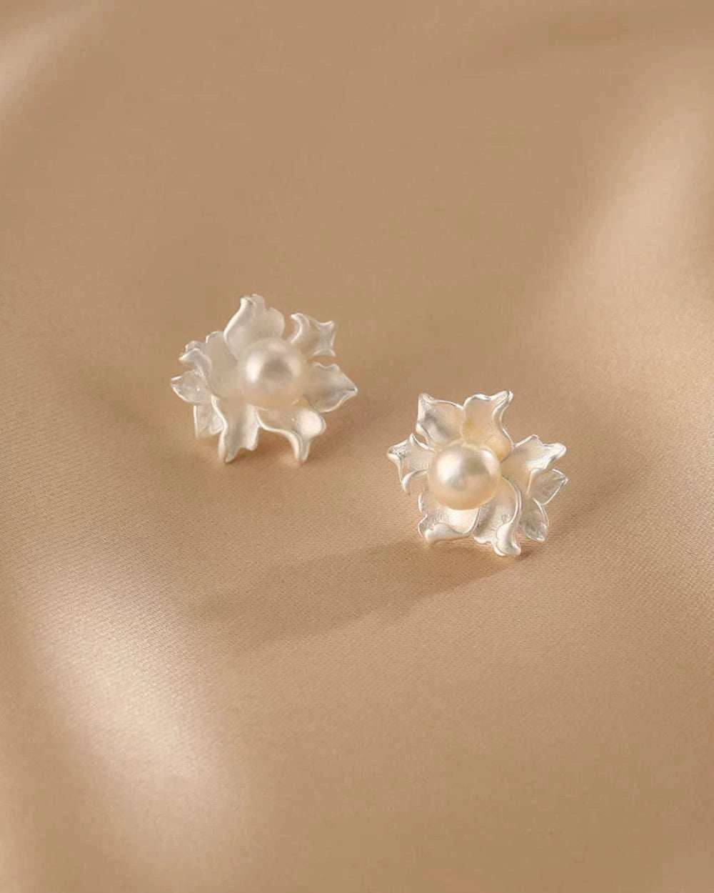 Pair of pearl flower earrings on a beige background