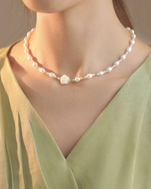 Pearl necklace worn by a person in a green top against a neutral background