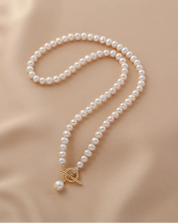 Pearl necklace with a gold clasp on a beige fabric background
