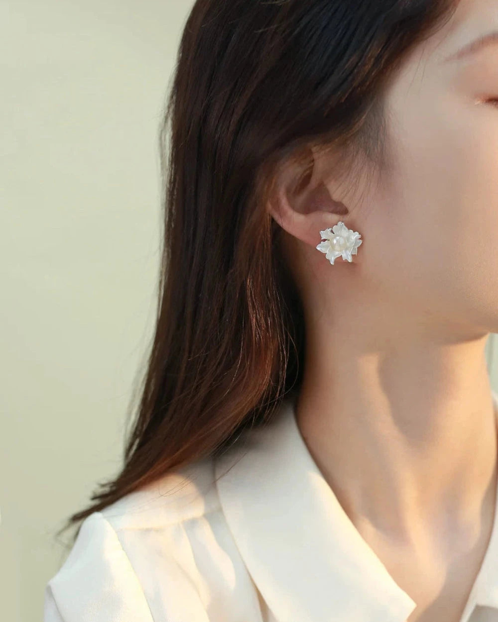 Close-up of a person wearing a floral earring with a plain background