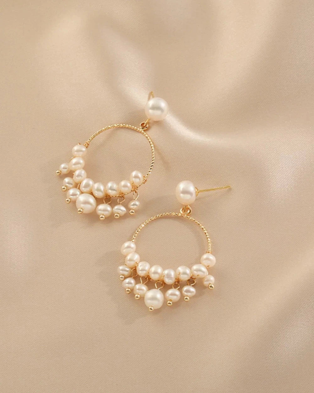 Gold hoop earrings with pearls on a beige background