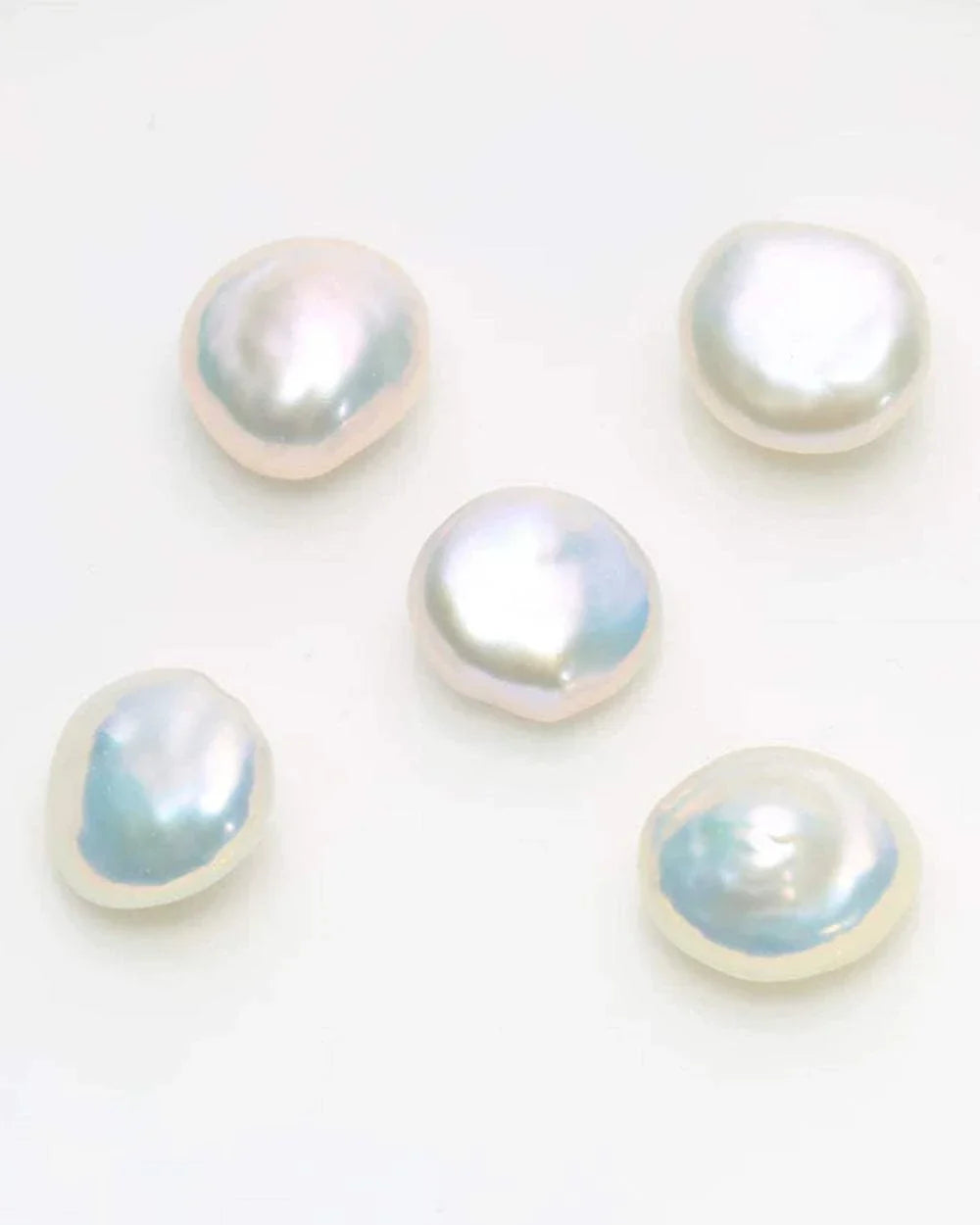 Five pearls of various shapes and sizes on a white background