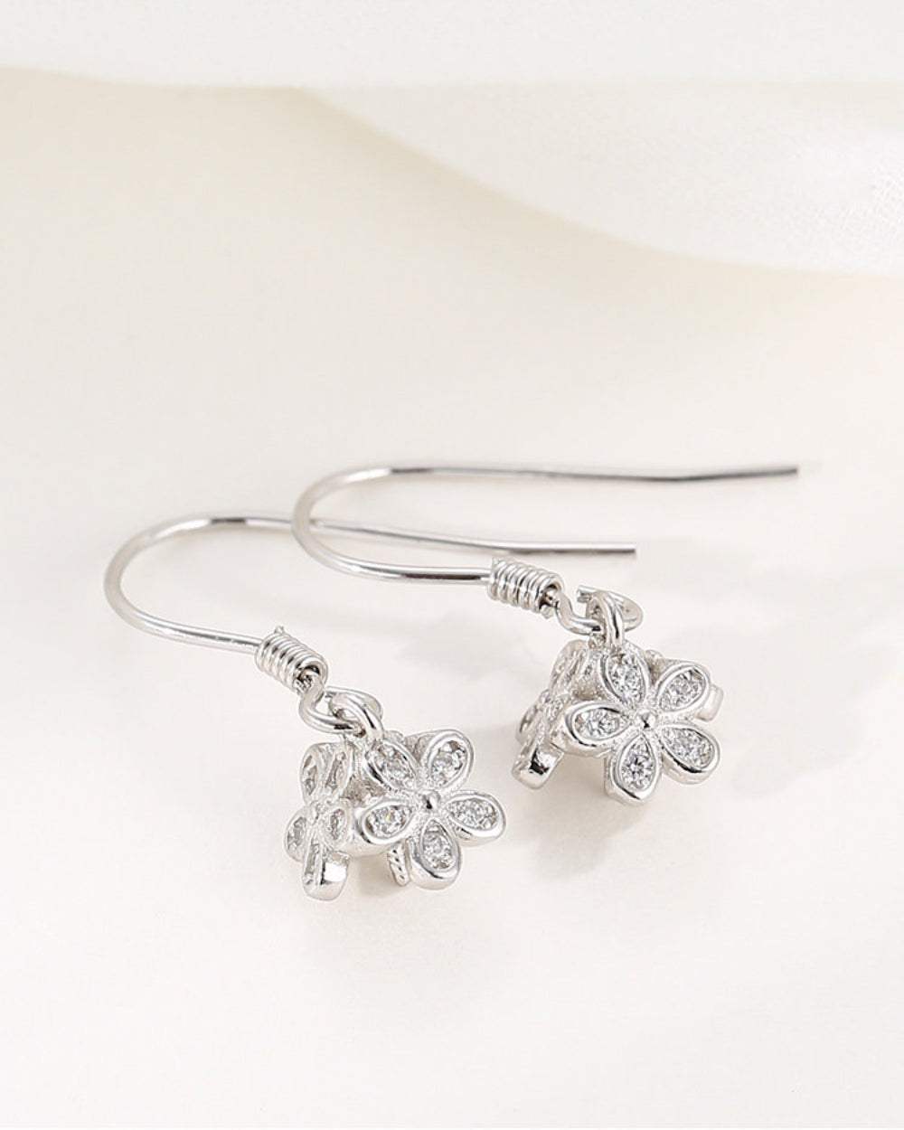 Silver earrings with floral designs on a white background